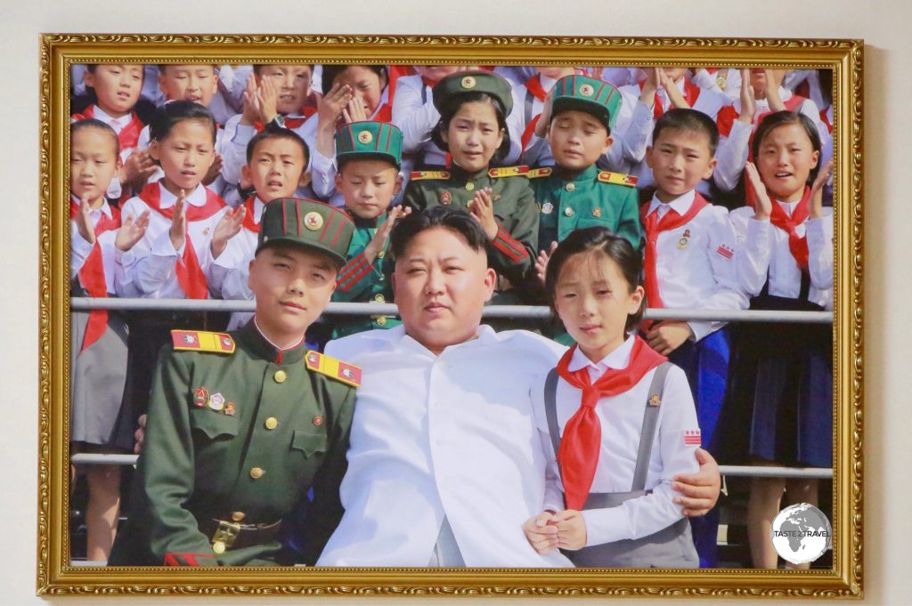 Although current leader Kim Jong-un’s image is not displayed publicly, there are photos and paintings of him featured in galleries. Notice the children behind him are crying tears of joy.