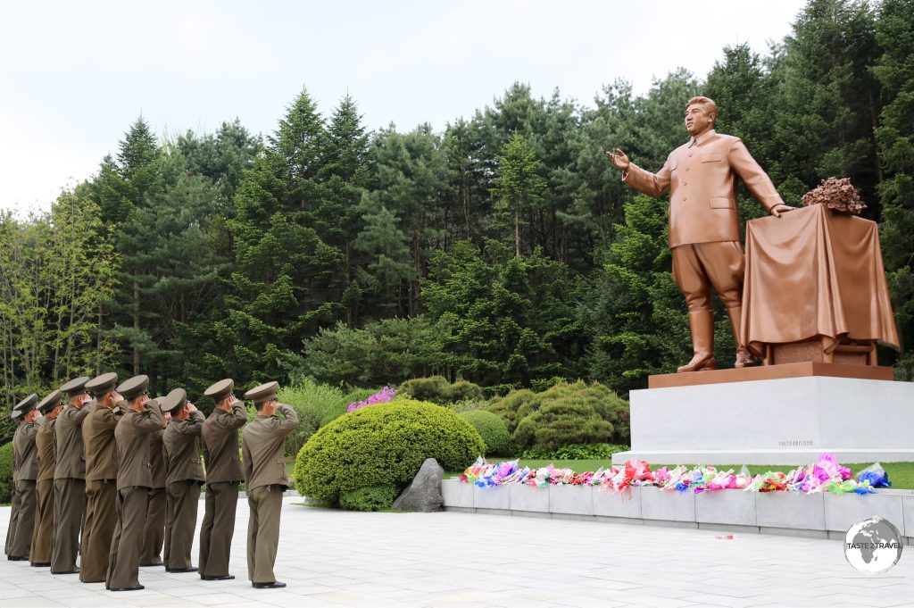 Soldiers salute in front of a statue of Kim il-sung in a park near Pyongyang.