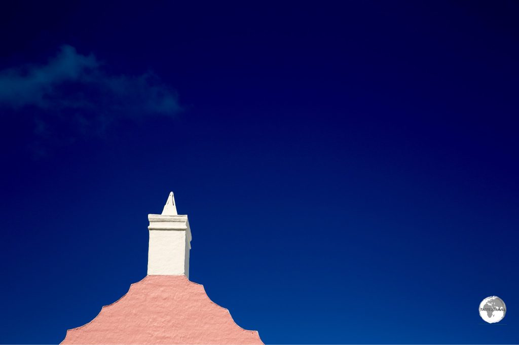 A pink gable and white chimney contrast nicely against the blue Bermuda sky.