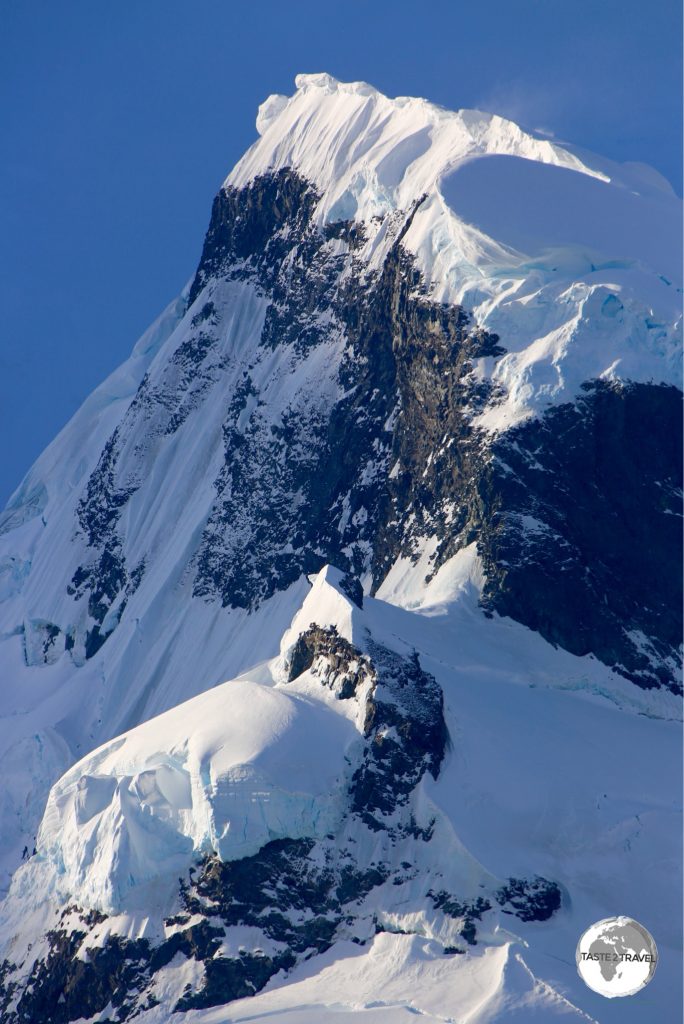Towering peaks line the shoreline of the narrow Lemaire channel.