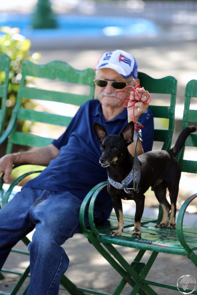 A proud dog owner relaxing in Cienfuegos' Parque José Martí.