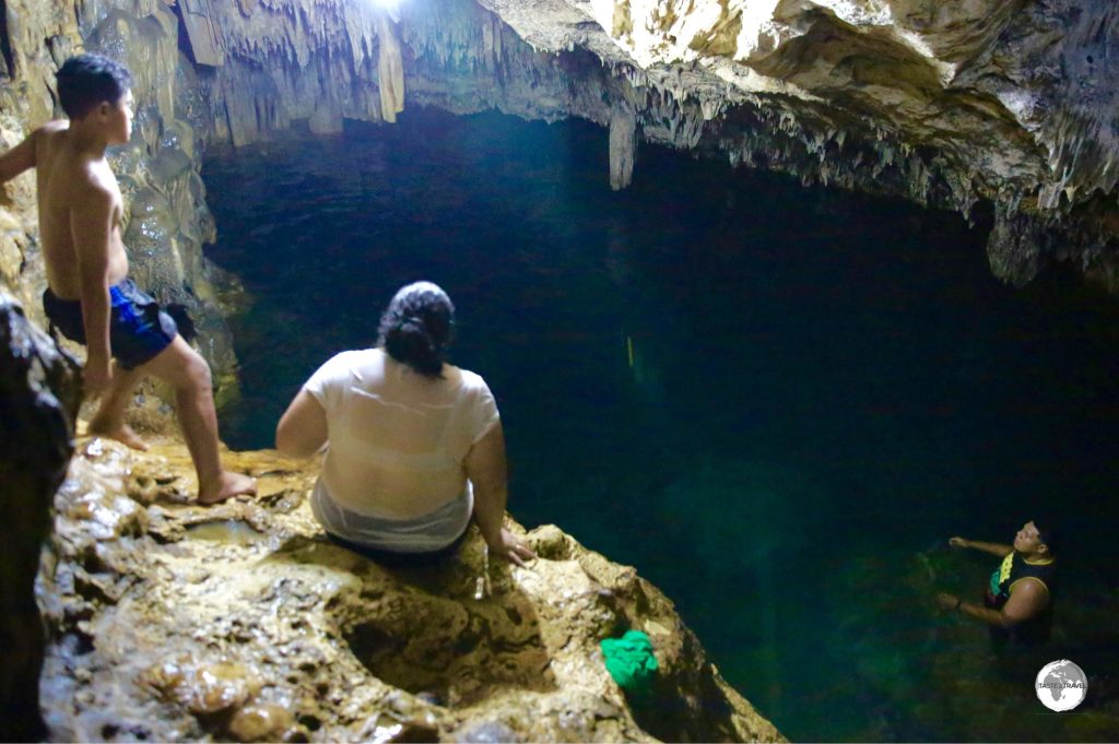 Locals bathing in the deep freshwater pool inside 'Anahulu Cave.