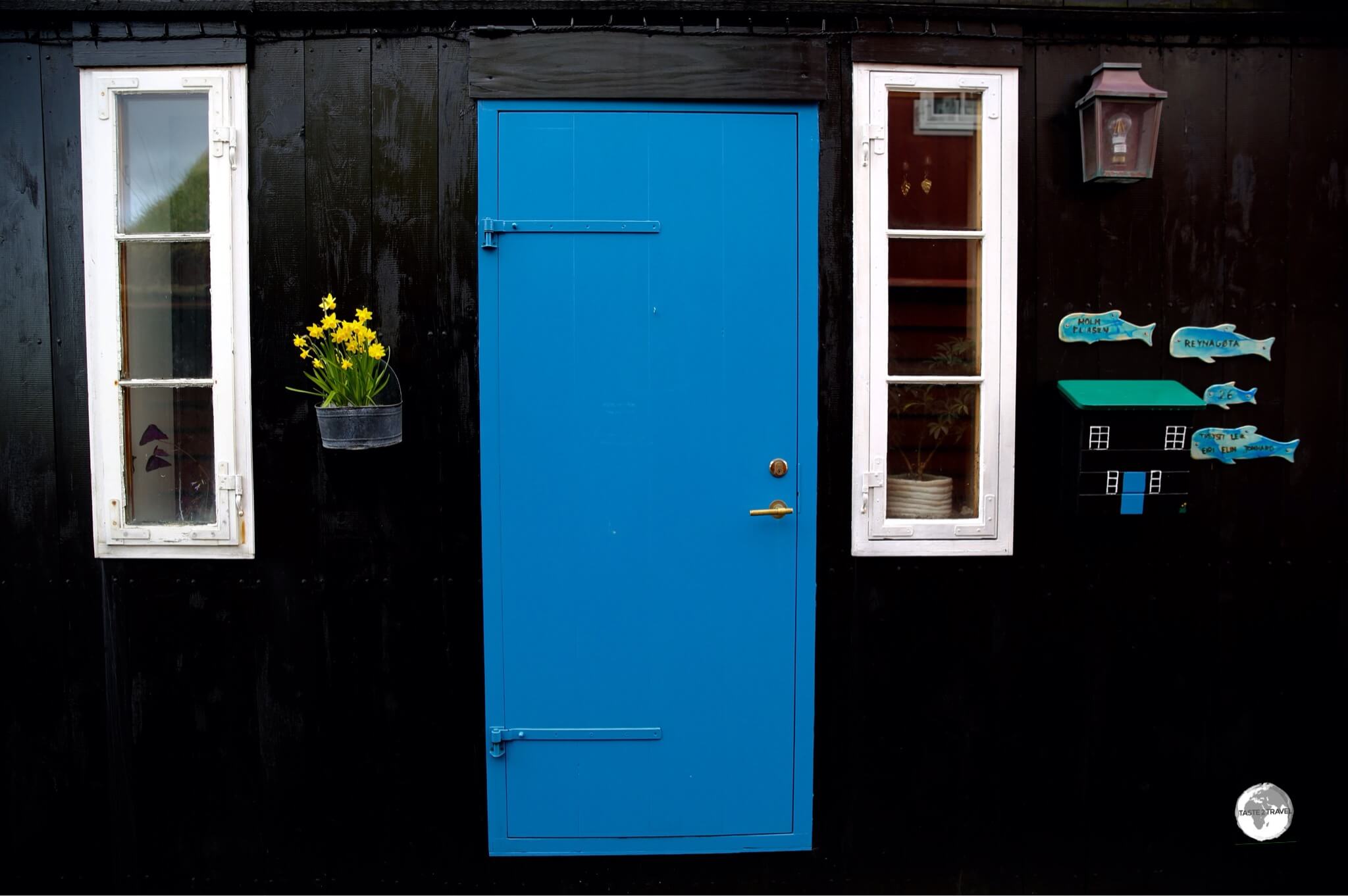 Despite being a treeless archipelago, many houses on the Faroe Islands are constructed from timber and painted glossy colours - including black. This makes for a nice contrasting background onto which colourful ornaments are added. Can you see the camouflaged mailbox?