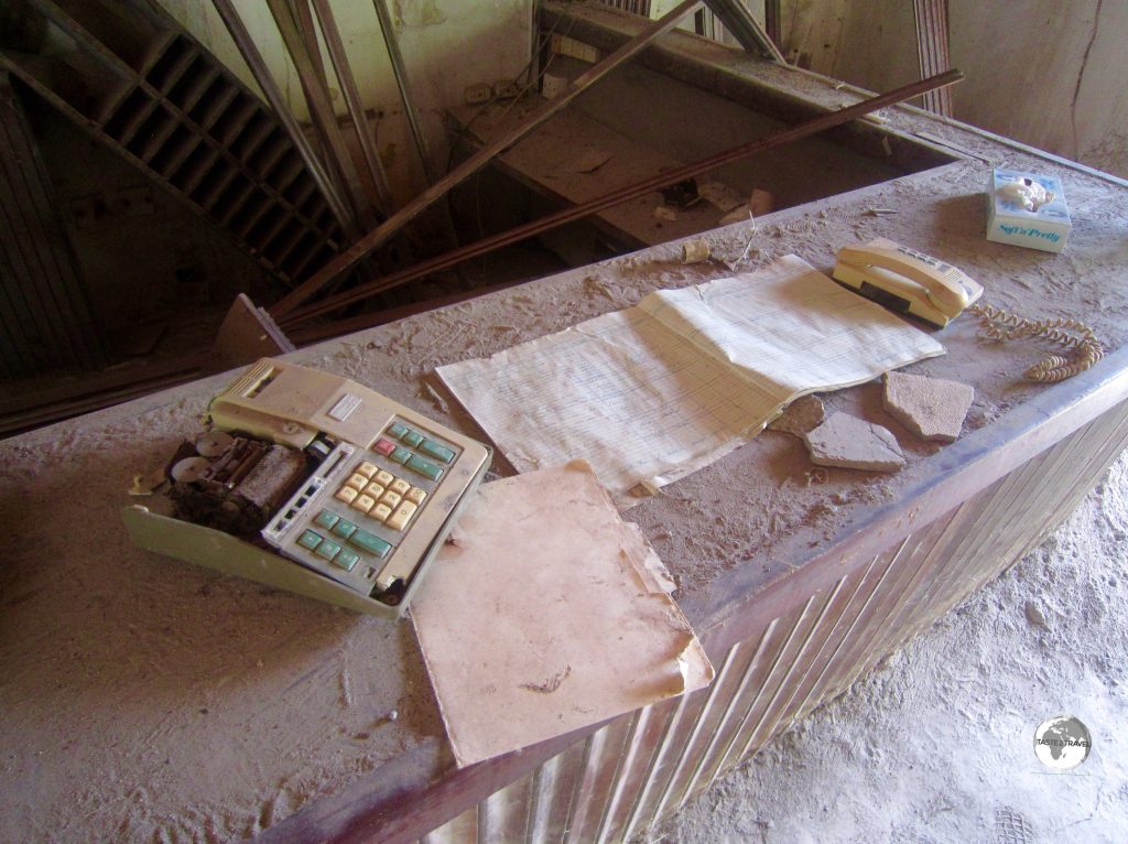 A calculator and ledger book remain on the reception desk of the abandoned Montserrat Springs Hotel,