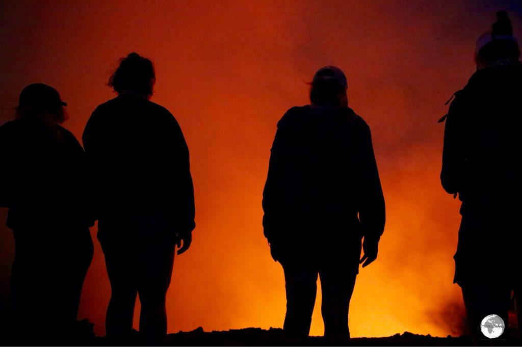 Observers illuminated by the glow from the volcano.