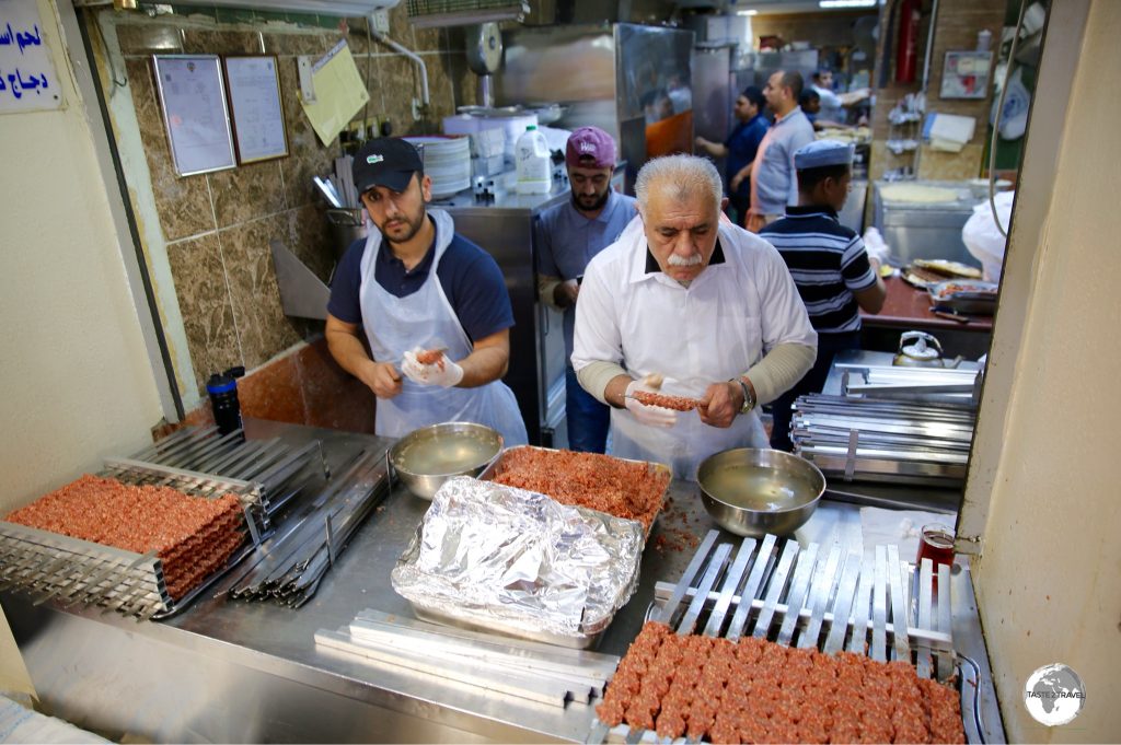 Two chefs preparing many Kofte shish kebabs at Souk Al-Mubarakiya.