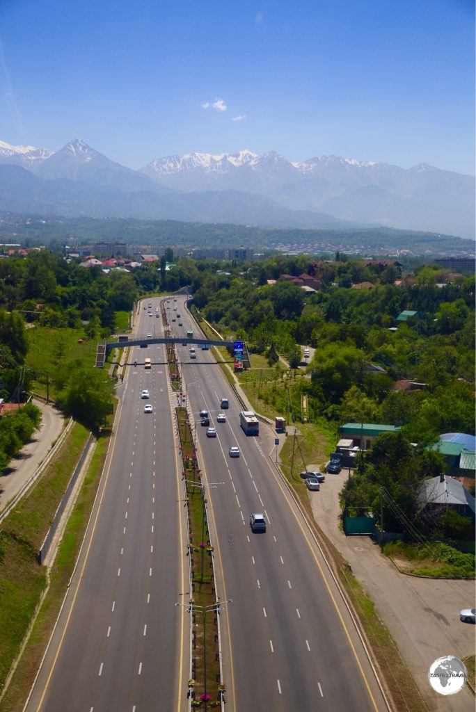 A view of a highway in Almaty with the Tien Shan mountains in the background.