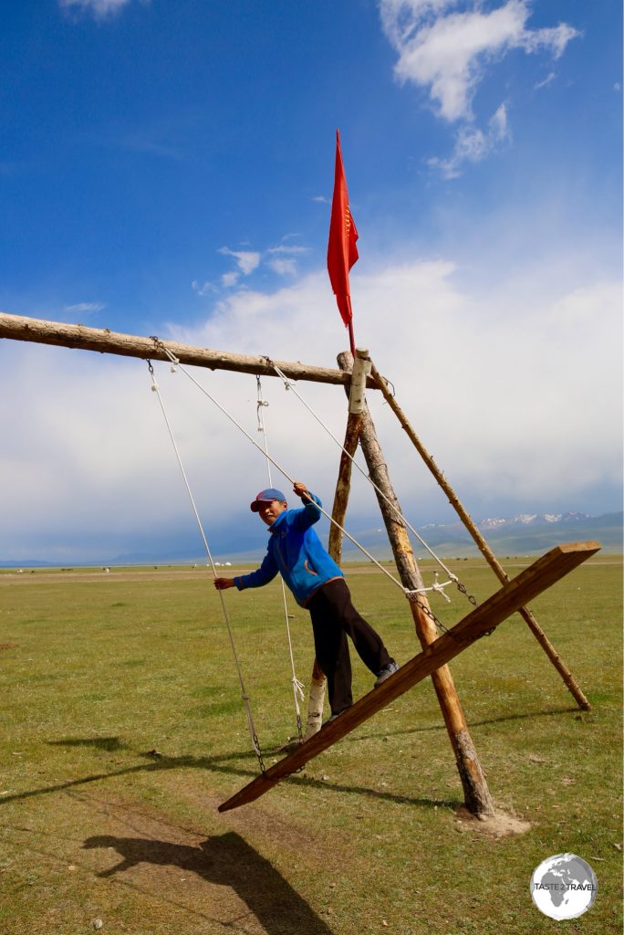 A young boy playing on a traditional Kyrgyz swing on the shore of lake Son-Kul.