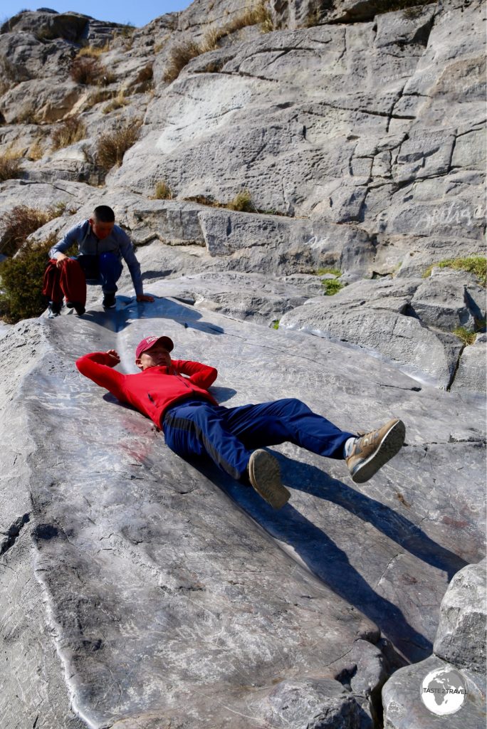 Locals sliding down the polished limestone rock on Sulaiman-Too.