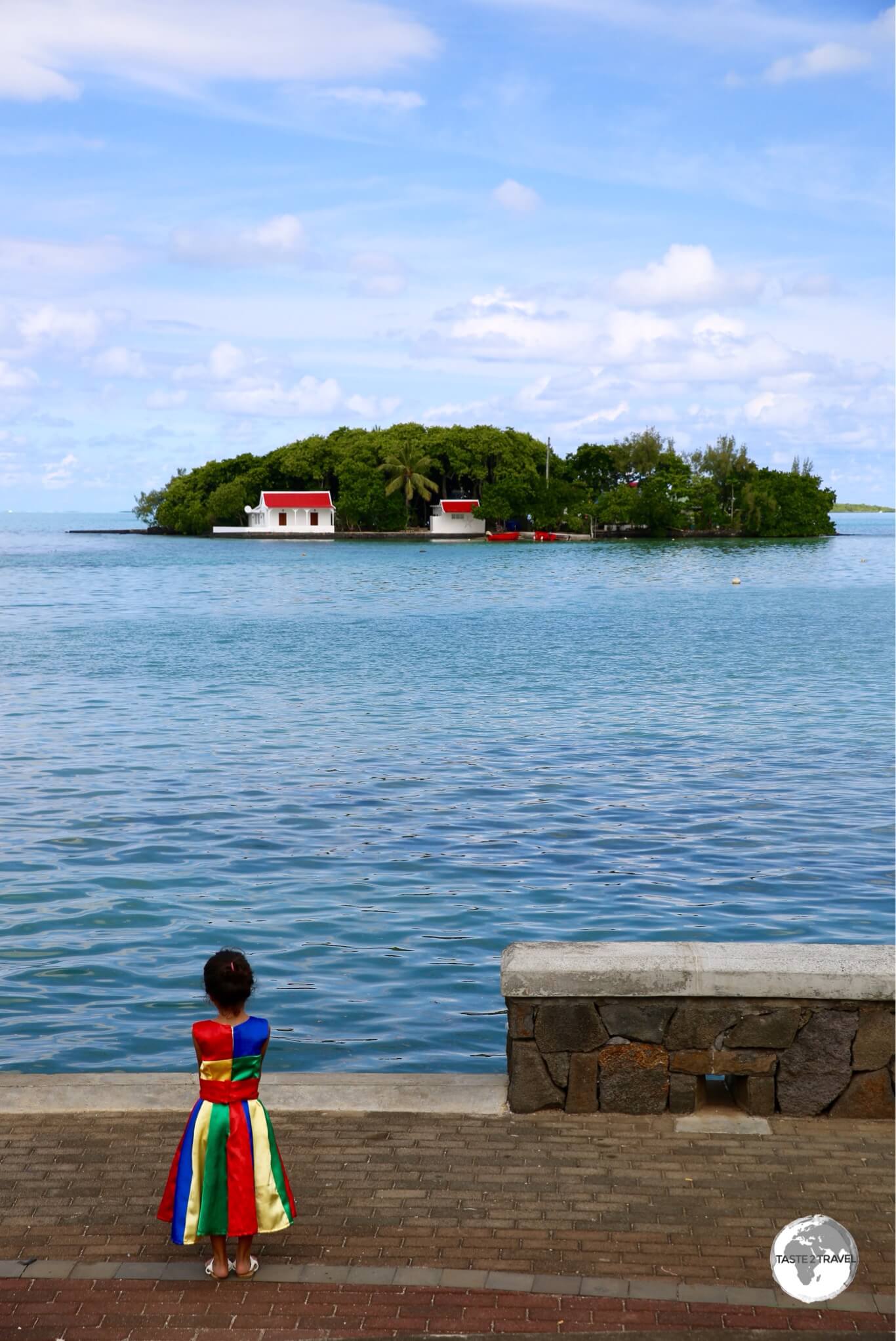 A young girl at Mahébourg, wearing the Mauritius national colours, with the island of Mouchoir Rouge in the background.