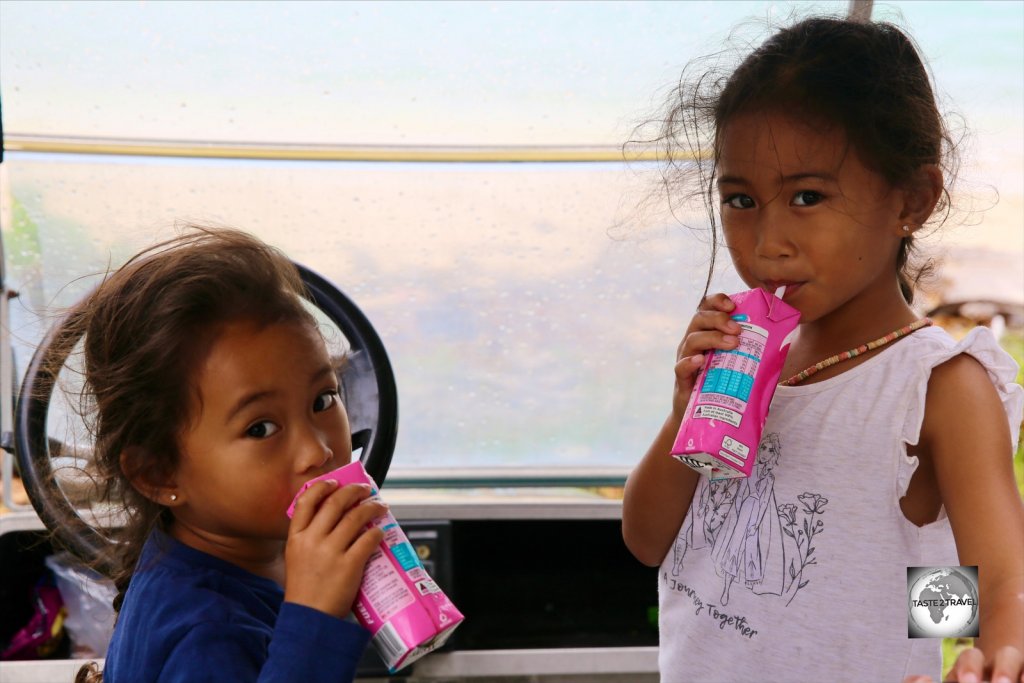 Two Cocos Malay girls, enjoying some strawberry milk, on Home Island.