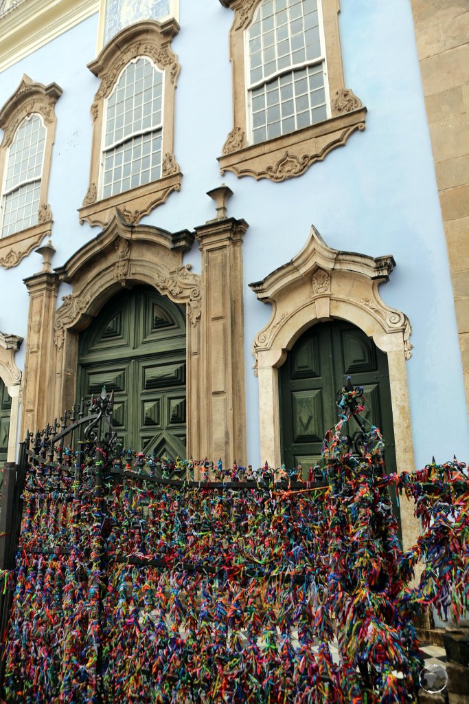 Colourful 'Wish Ribbons' tied to a wrought-iron gate in front of a church in Salvador, Brazil.