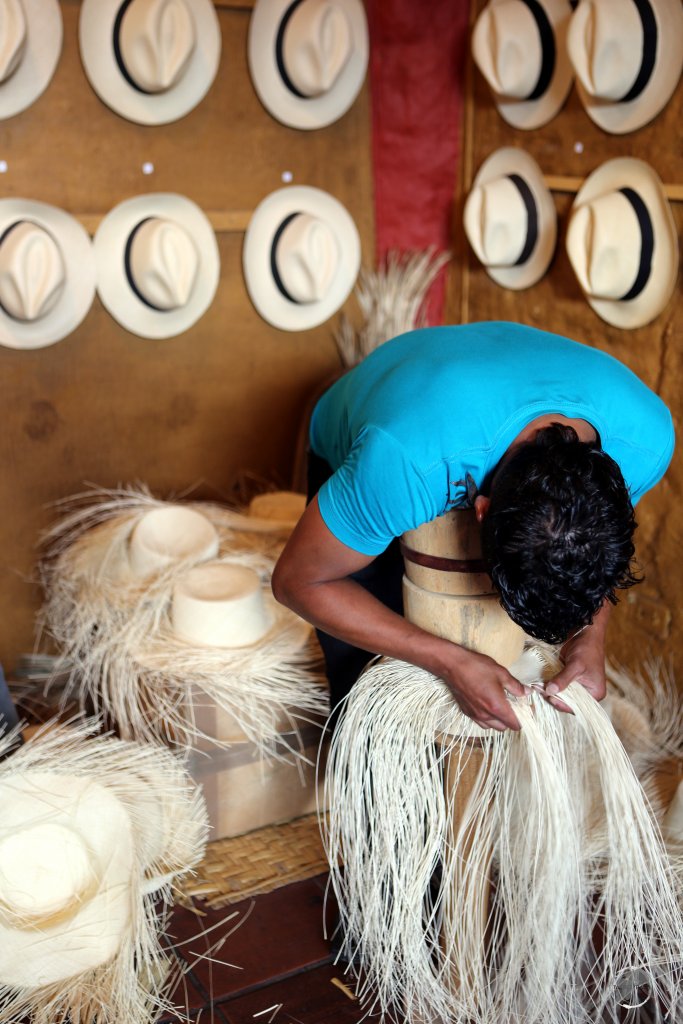 Weaving a Panama hat is back breaking work, requiring the weaver to hold the hat in place using a wood form and their own weight, while they slowly weave down the sides of the hat.