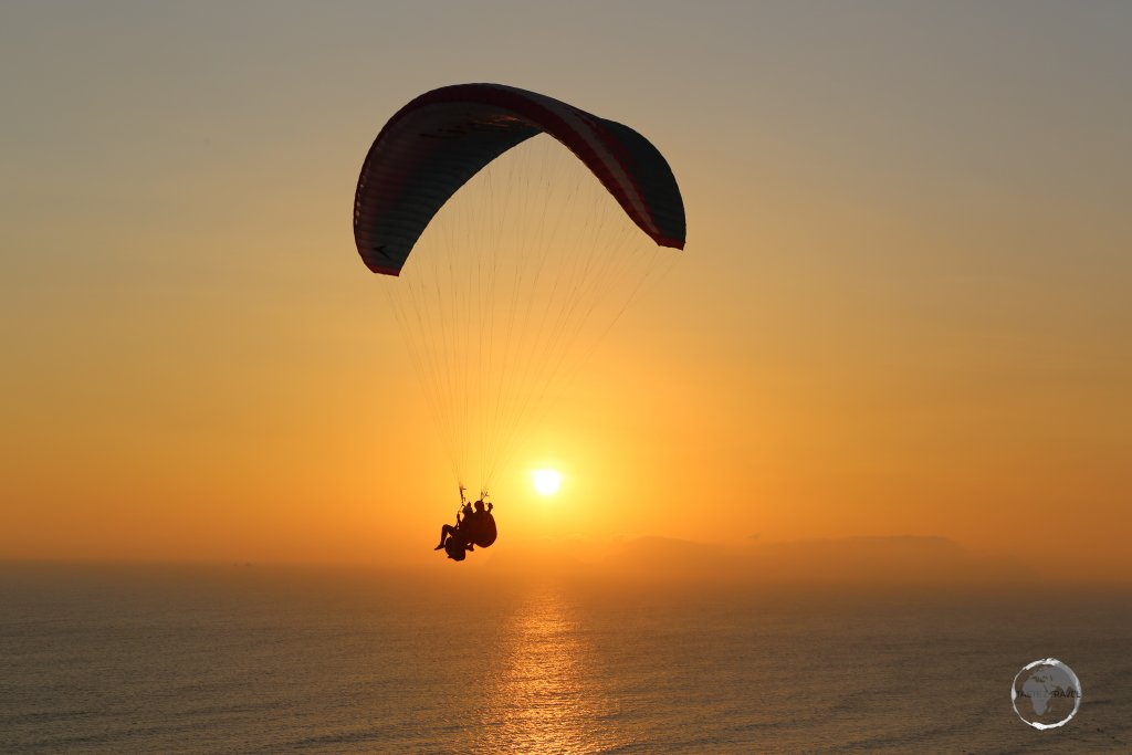Tandem paragliders taking in the sunset over the Pacific Ocean in Lima, the capital of Peru.