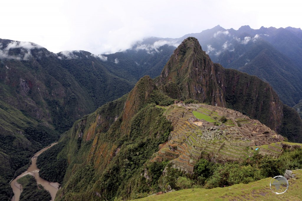 A panoramic view of Machu Picchu, which sits atop a steeply-side ridge, high above the Urubamba River at an elevation of 2,430 metres (7,970 ft).