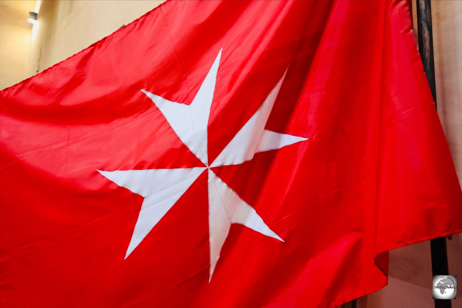 The flag of the Order's Works, featuring a white Maltese cross, inside the Casa dei Cavalieri di Rodi.