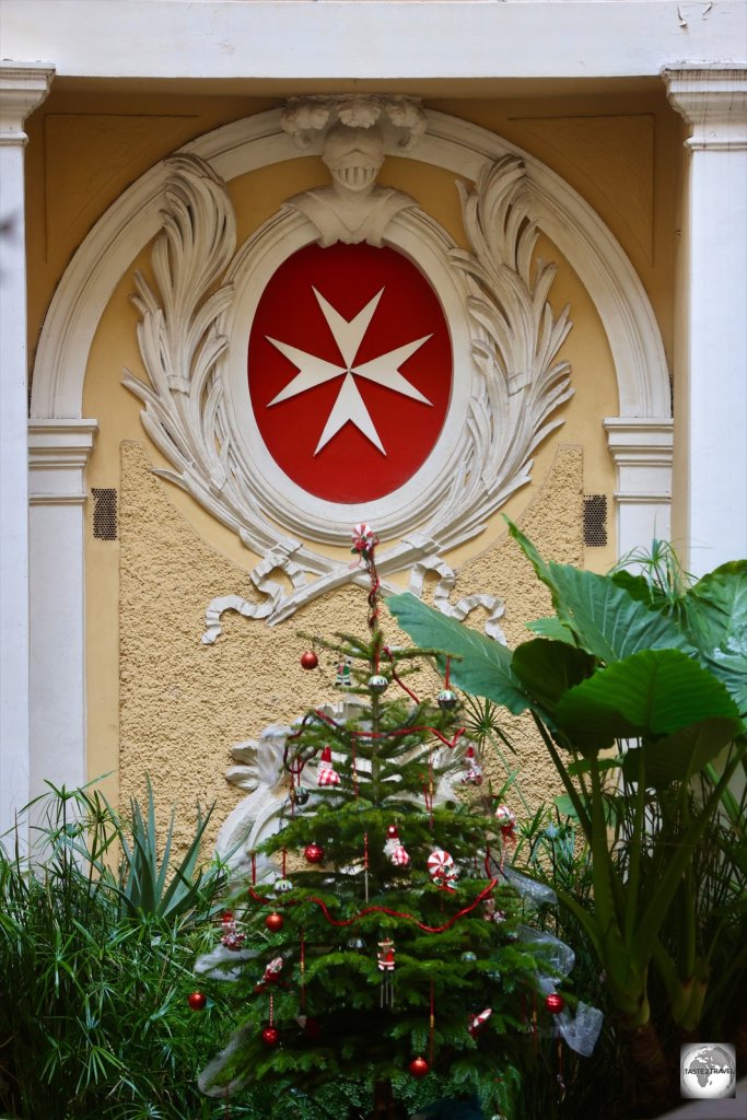 A Maltese cross adorns the rear wall of the courtyard at the Magistral Palace.