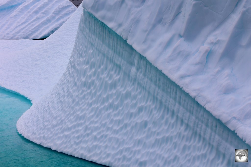 The rippling effect on this iceberg is caused by the action of water when the iceberg is submerged.