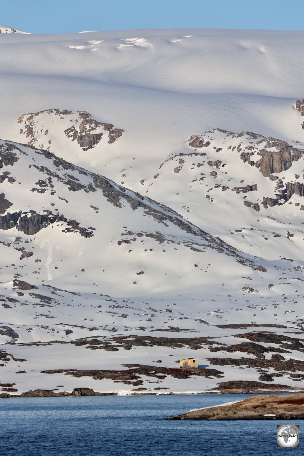 As seen from the sea, this summer house is built in the shadow of the, icing-smooth, Greenland Ice Sheet.