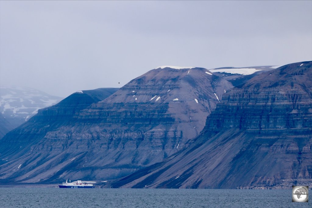 A cruise ship is dwarfed by the towering mountains of Svalbard.