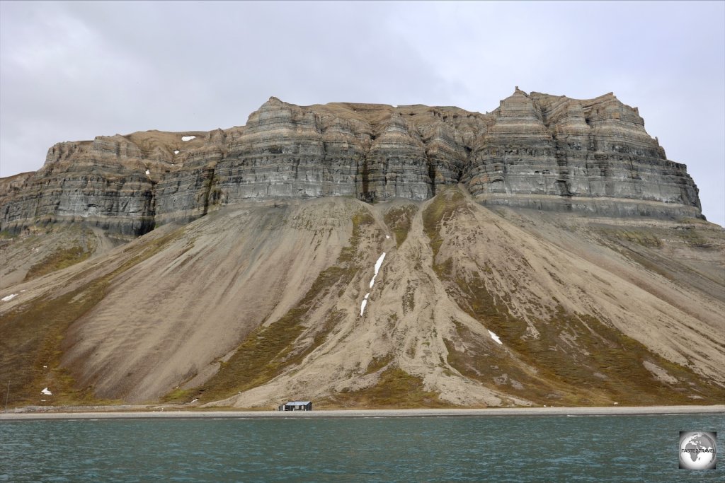 A beach cabin provides a sense of scale for the monumental scenery on Svalbard.