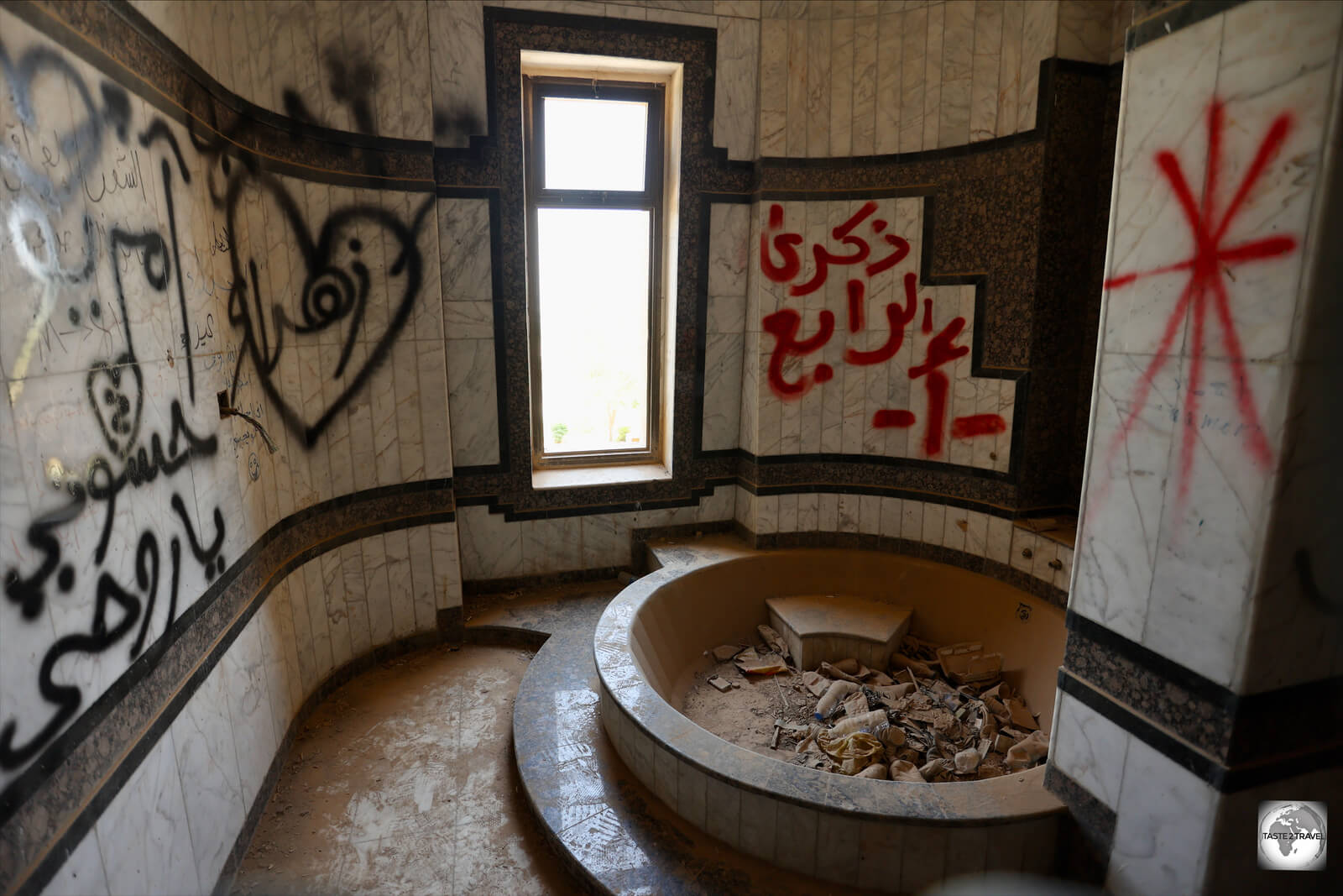 A former, marble-clad, bathroom is now covered in graffiti.