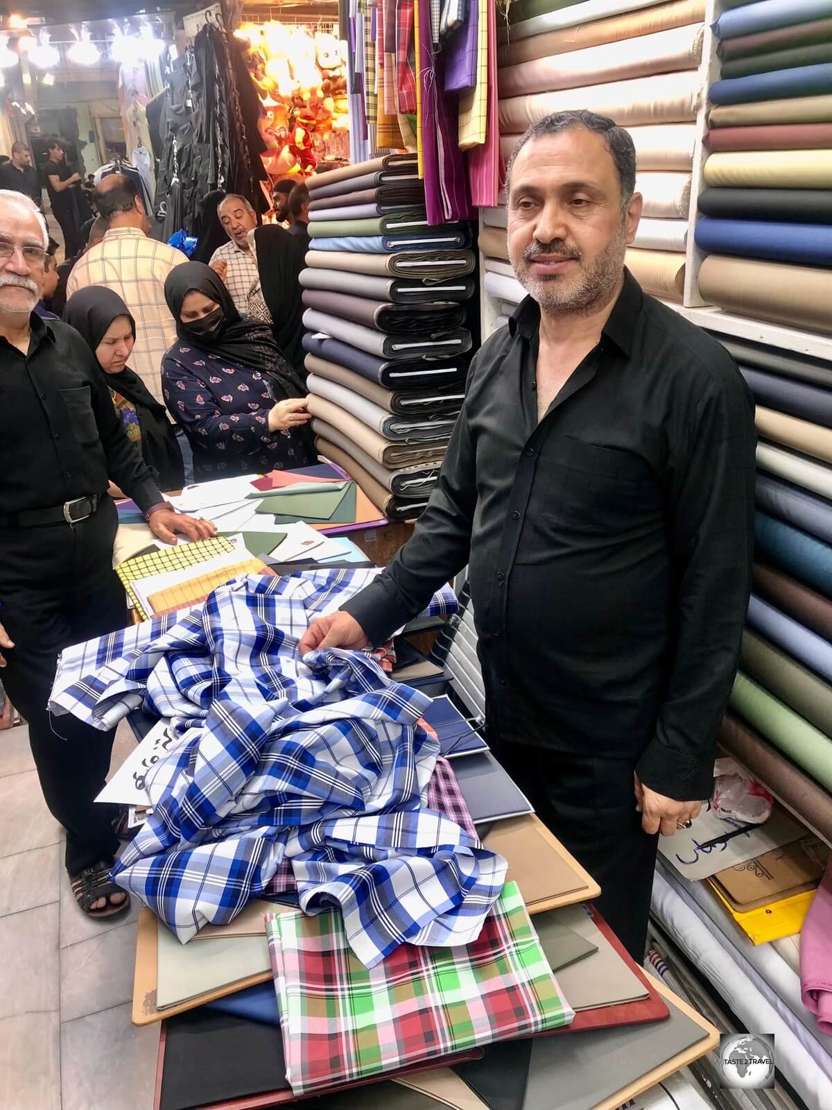 Selecting material for a new shirt from a tailor in Najaf souk.