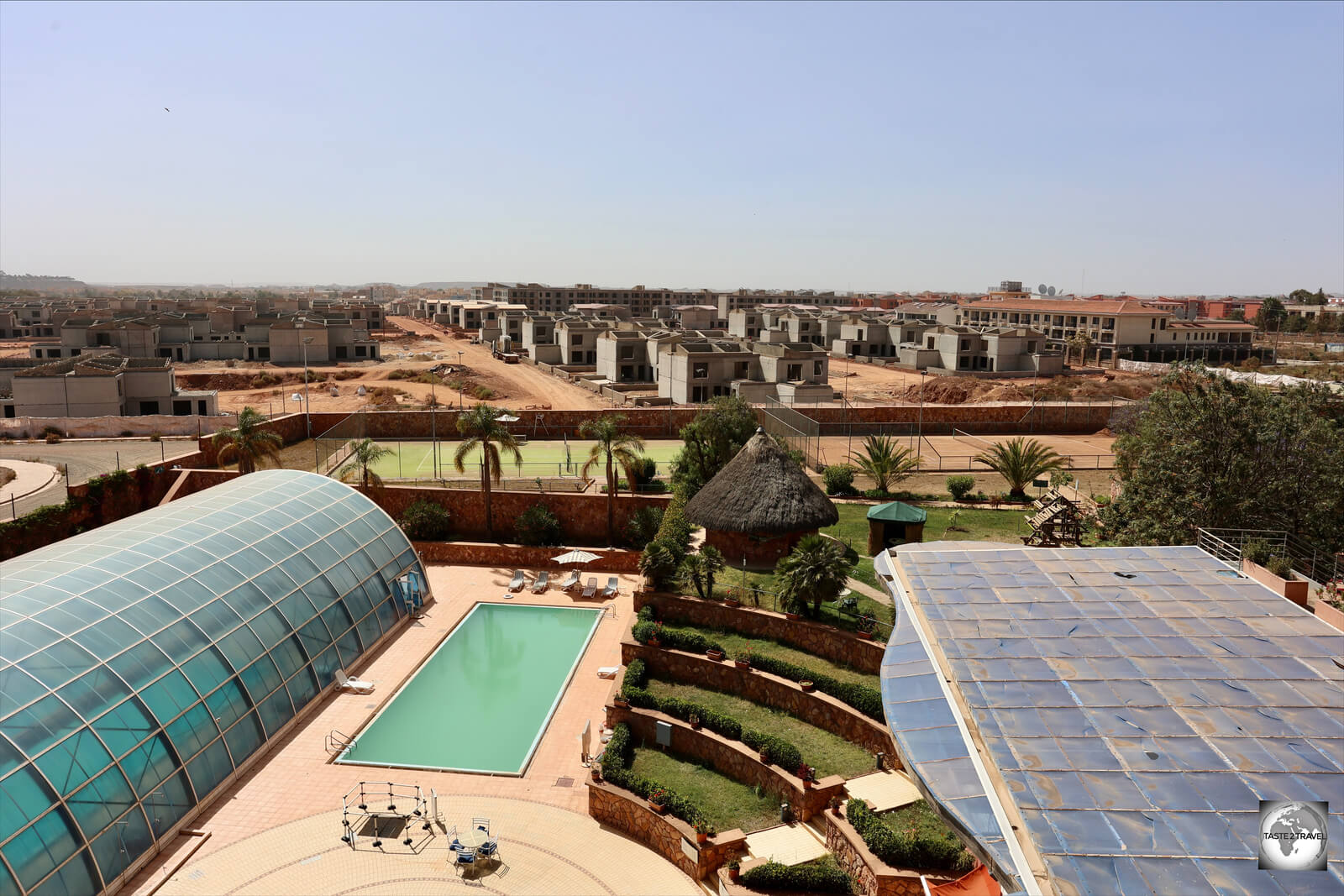 The view, from the balcony of my room, which shows the glass enclosure of the indoor pool, the outdoor pool and the tennis courts in the rear.