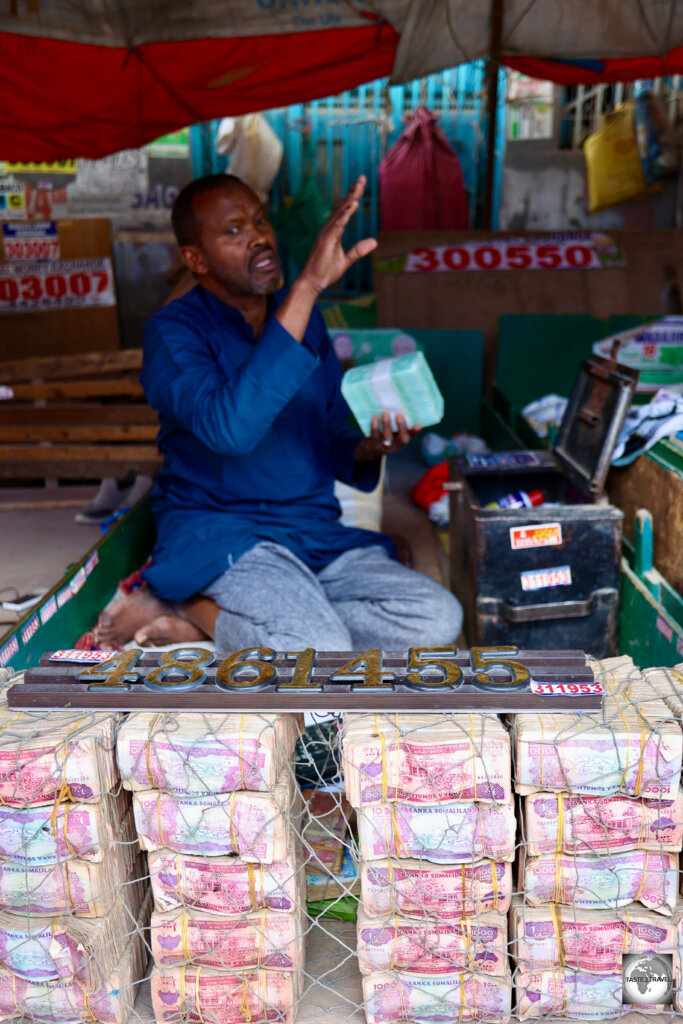 A money changer retrieving a wad of 1,000 uncirculated bank notes from his safe box.