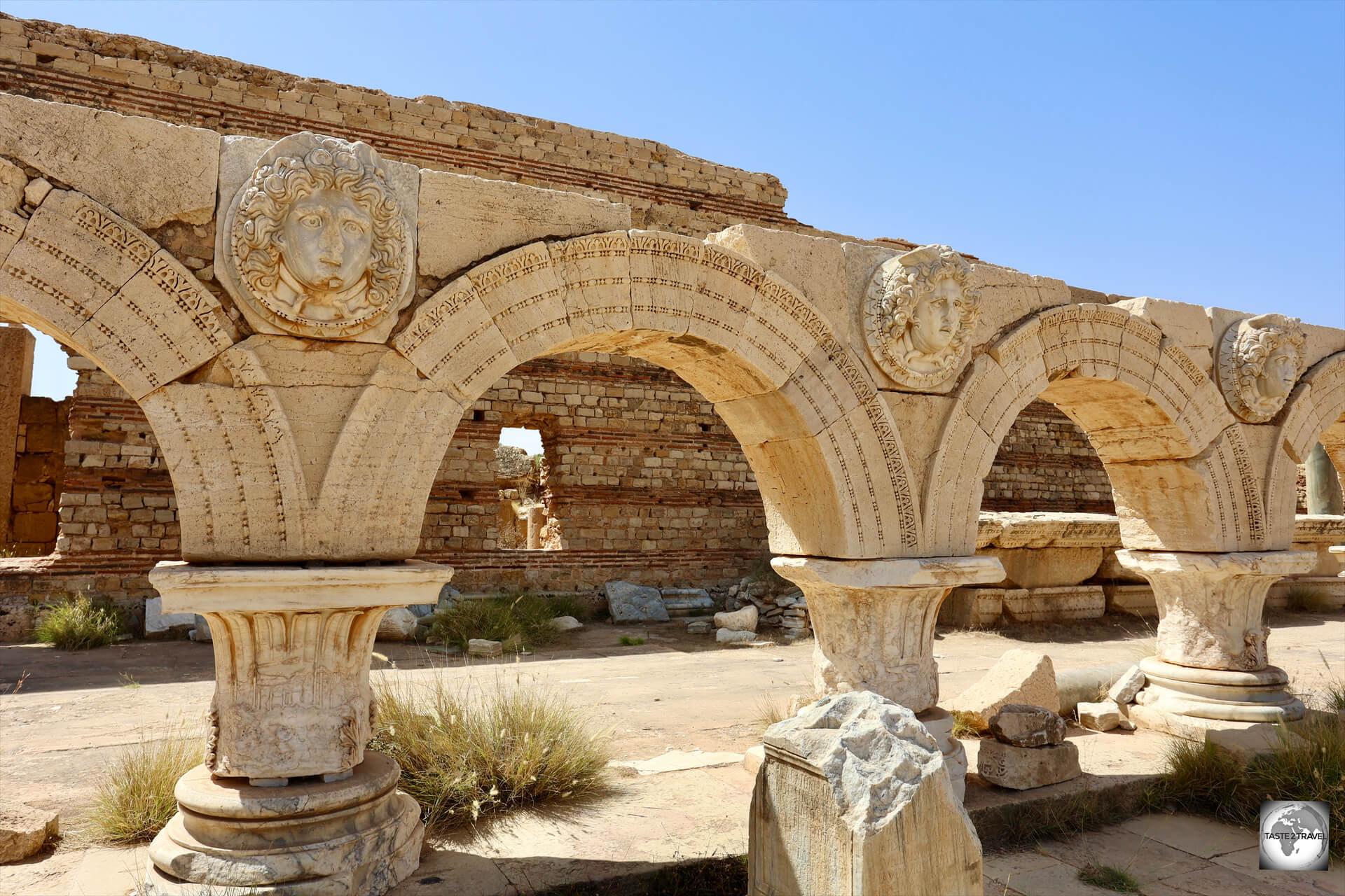 Arches, with Medusa heads, line one side of the Severan Forum at Leptis Magna.